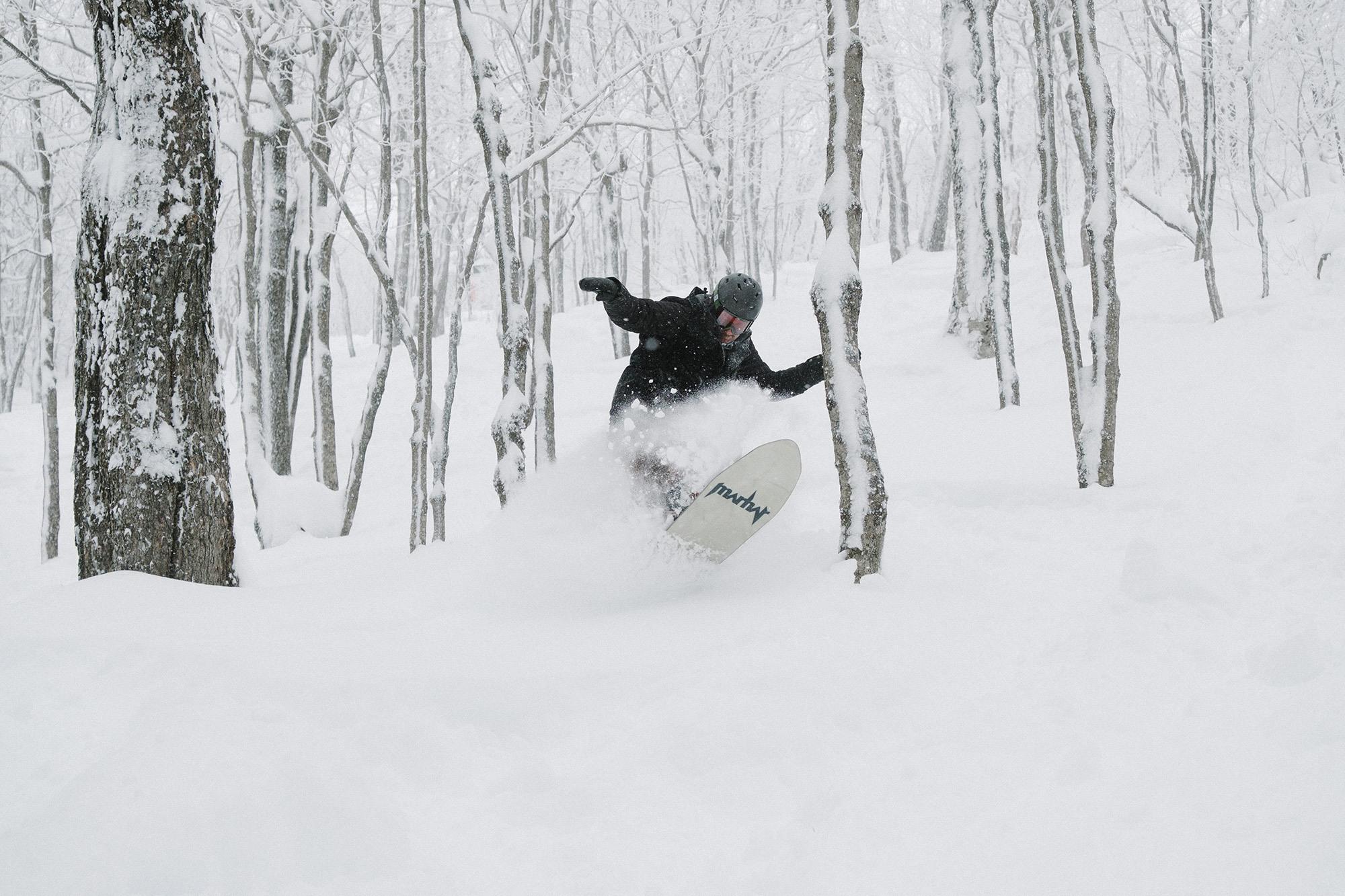 snowboarder riding glade in powder snow
